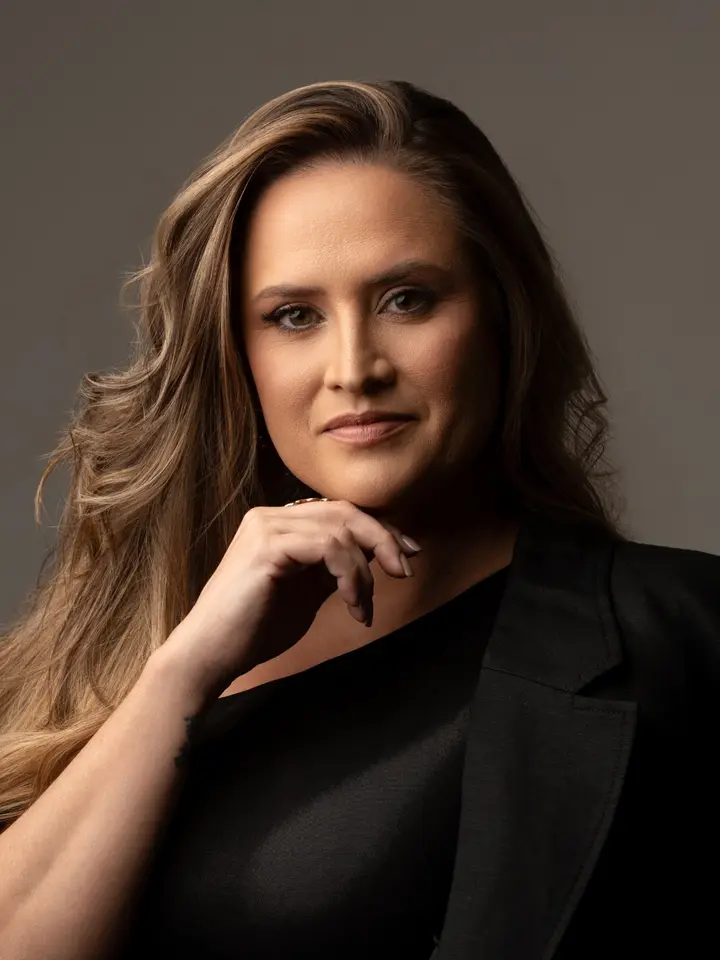 Letycia Romanini, de roupa preta, em retrato com fundo cinza.
